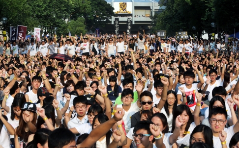 Le poing levé, en tee-shirts blancs (couleur du deuil), des milliers d'étudiants de l'Université de Hong Kong manifestent le 23 septembre