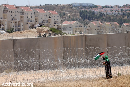Une femme palestinienne dépose un drapeau palestinien devant le mur de séparation en face de la colonie de Modi'n Illit